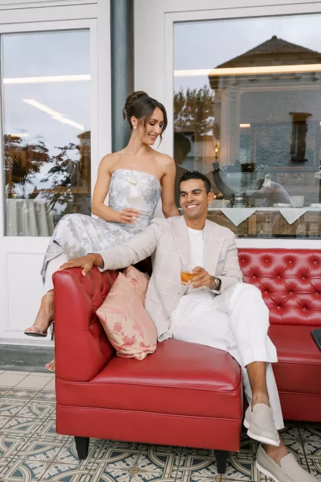 Couple sharing drinks on the red sofa terrace of Hotel Château Gütsch, surrounded by soft evening light.