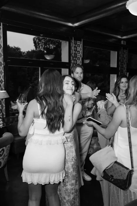 Joyful black and white photo of friends embracing during a celebration at Hotel Château Gütsch.