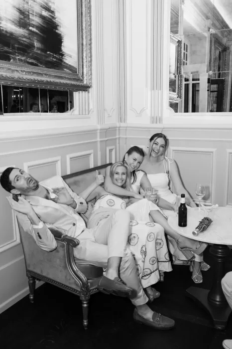 Black and white photo of friends relaxing on a vintage sofa inside Hotel Château Gütsch’s elegant lounge.