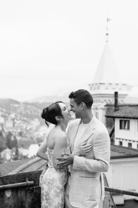 Joyful couple laughing together on the terrace of Hotel Château Gütsch with Lucerne’s skyline behind them.