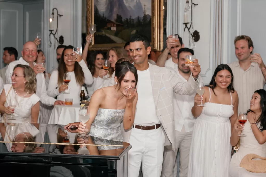 Couple raising glasses in laughter with guests during a joyful celebration at Hotel Château Gütsch.