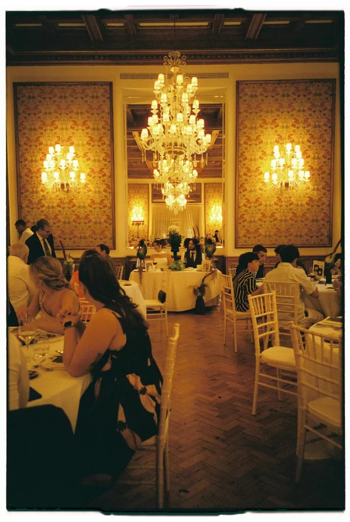 Wedding reception inside Infante Sagres ballroom with grand chandeliers, candlelit tables, and guests dining beneath ornate ceilings.