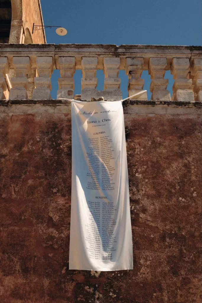 Long fabric banner listing guest names hanging against the rustic exterior wall of Masseria Spina.