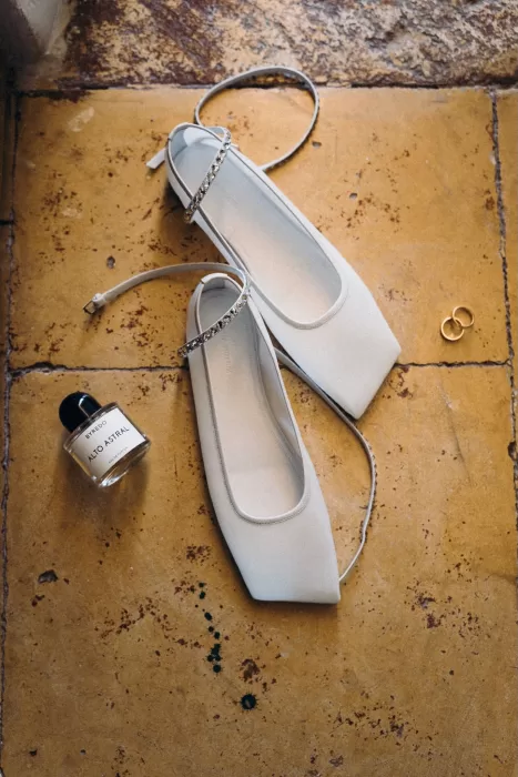 Bridal shoes, perfume, and wedding rings styled on rustic stone flooring at Masseria Spina.