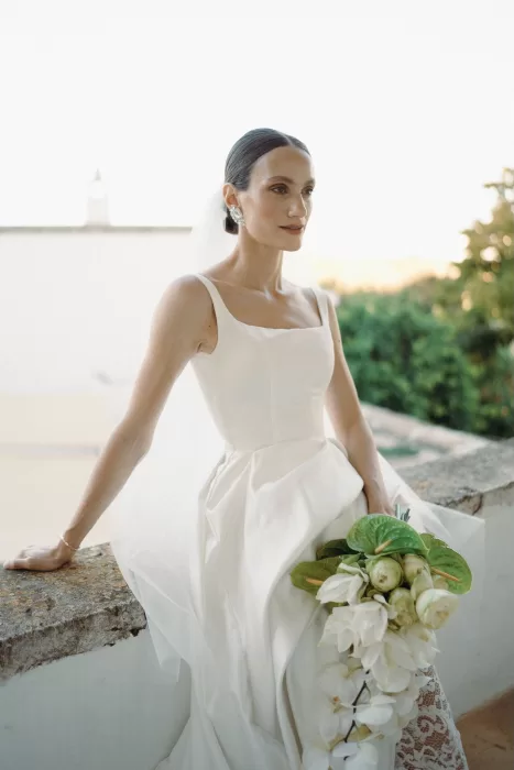 Elegant bride posing on a terrace at Masseria Spina, holding a cascading white bouquet.