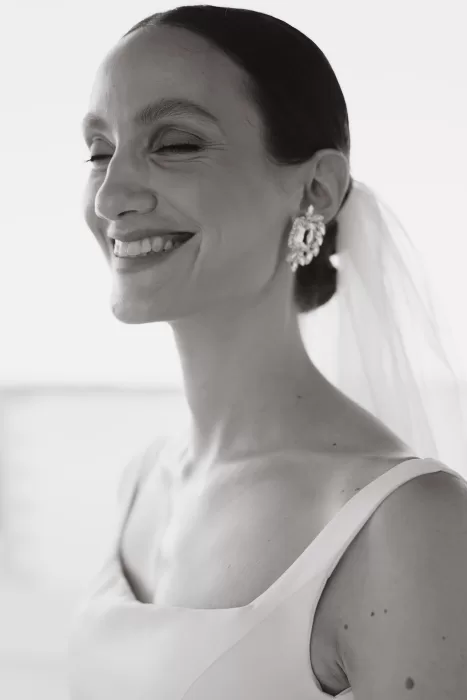 Radiant close-up of the bride smiling with her veil and statement earrings at Masseria Spina.
