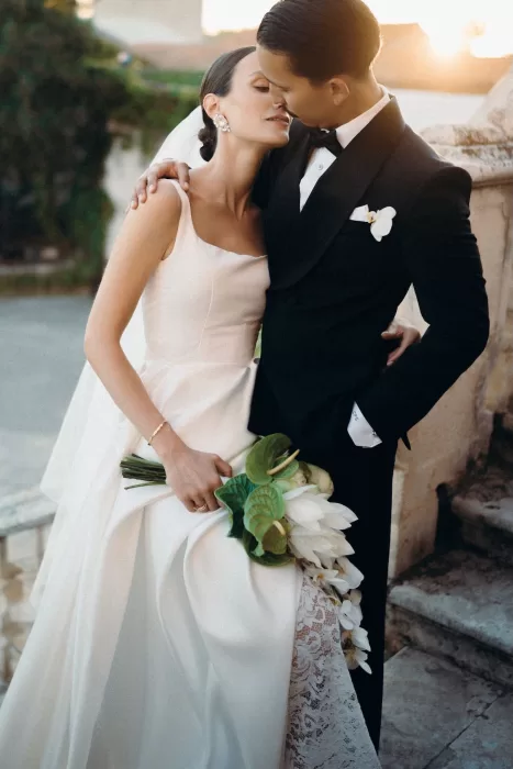 Romantic moment of the couple embracing at sunset on the stone steps of Masseria Spina.