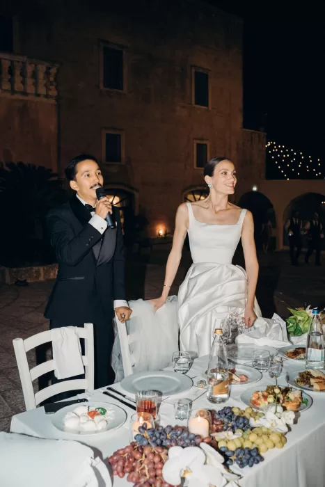 Bride and groom giving a toast during their evening reception at Masseria Spina, surrounded by candlelit tables.