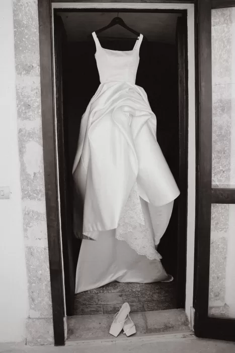 Wedding dress hanging in a doorway at Masseria Spina with the bride’s shoes placed below.