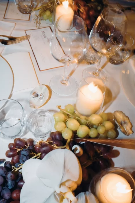 Close-up of candlelit reception table at Masseria Spina with grapes, orchids, and elegant glassware.