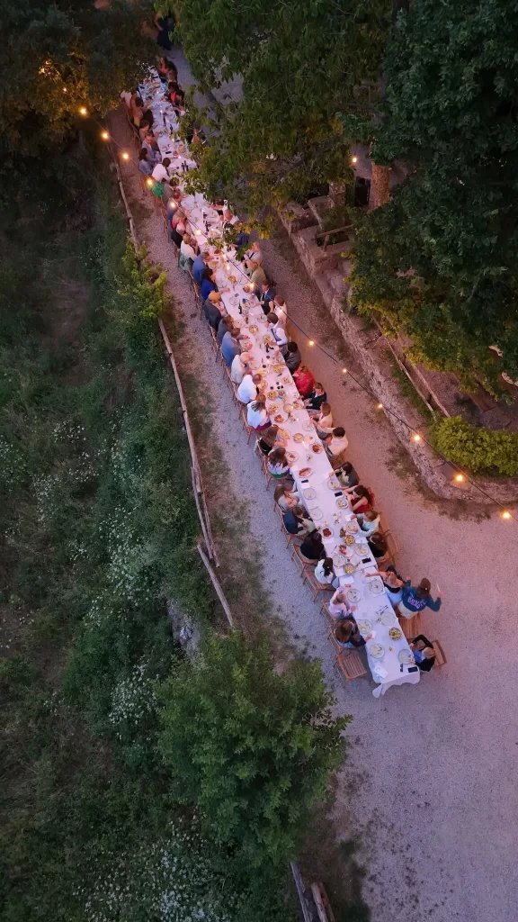 Guests dining at a long outdoor table under string lights at Novanta 90 during a summer evening celebration.