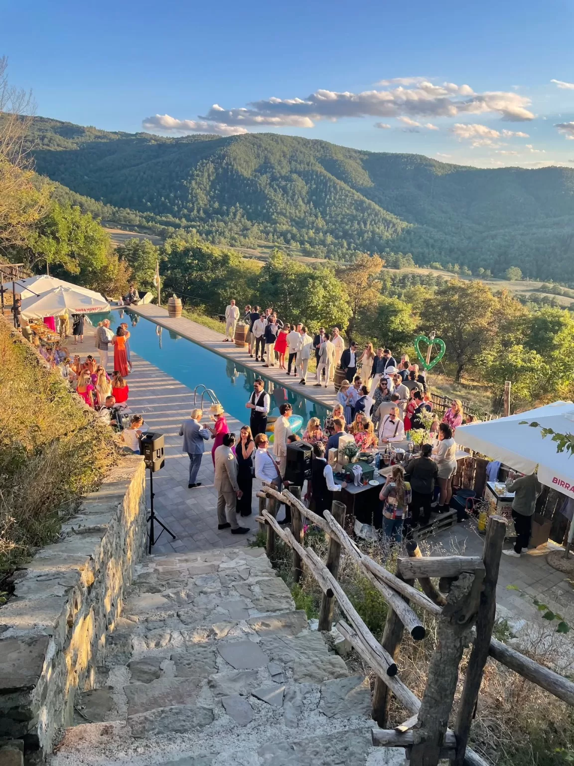 Wedding guests mingling beside the infinity pool at Novanta 90 with sweeping views of the Tuscan hills.