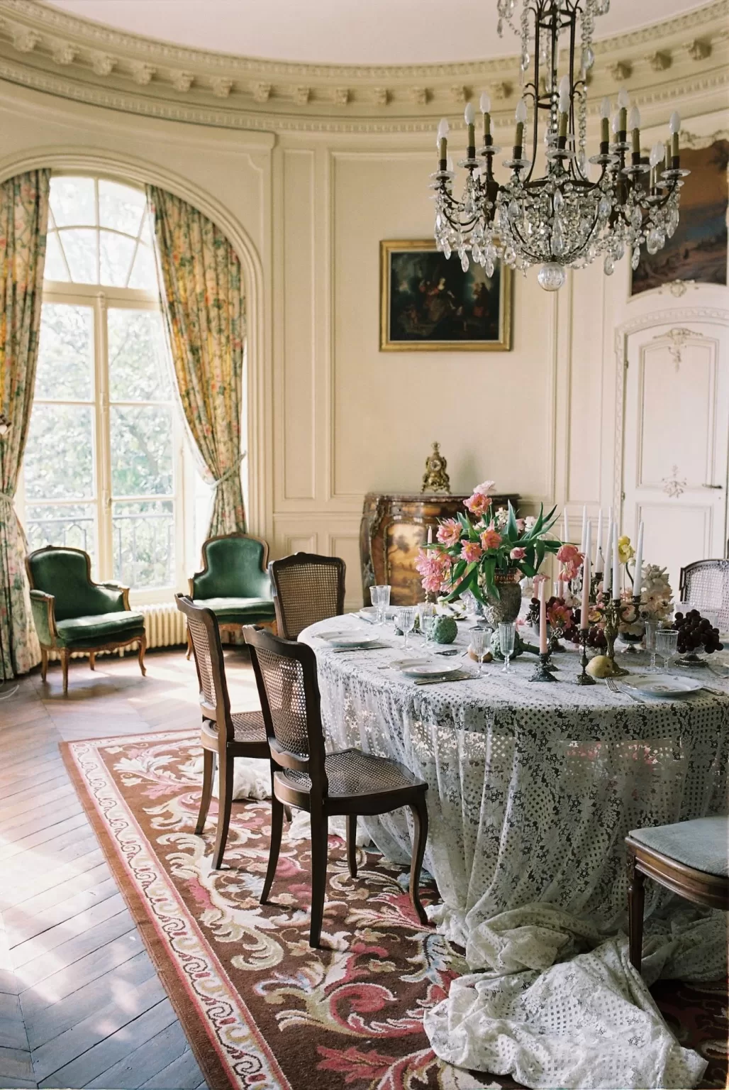 Romantic bedroom at Château du Prieuré featuring a green velvet bed, floral wallpaper, and soft morning light.