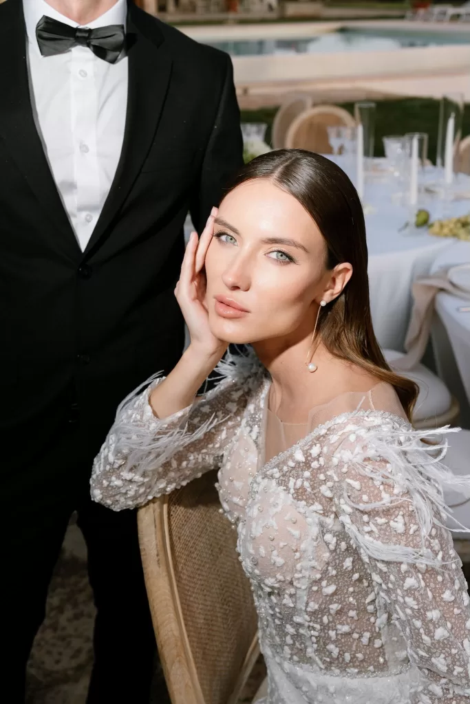 Close-up of bride in a beaded gown with feather details, seated at the reception table in Apulien, Bari.