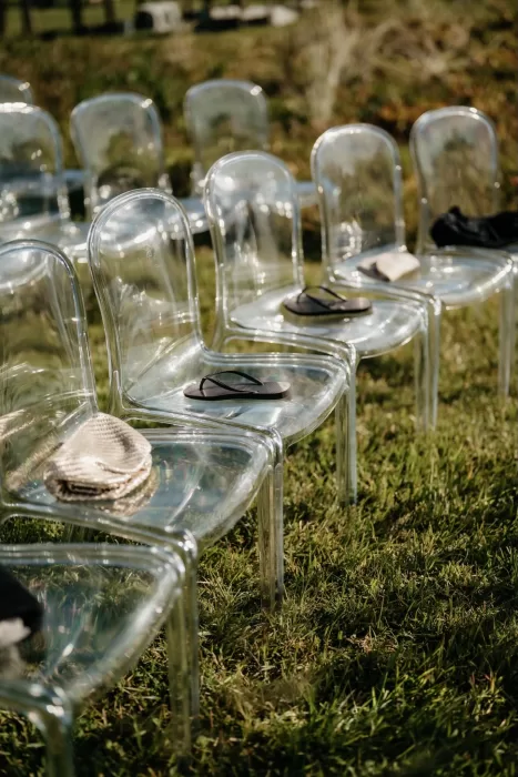 Clear ceremony chairs arranged on the lawn at Areias do Seixo, set for an outdoor wedding.