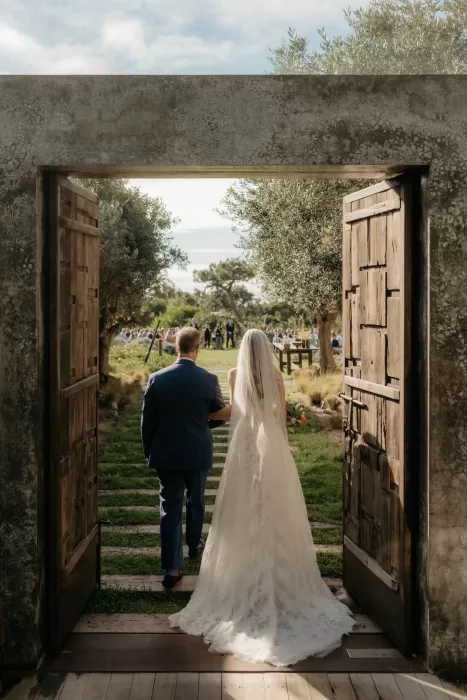 Bride entering the outdoor ceremony space through wooden doors at Areias do Seixo.