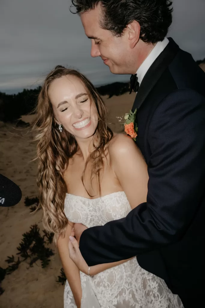 Intimate portrait of the bride and groom embracing in the sand dunes at Areias do Seixo at golden hour.