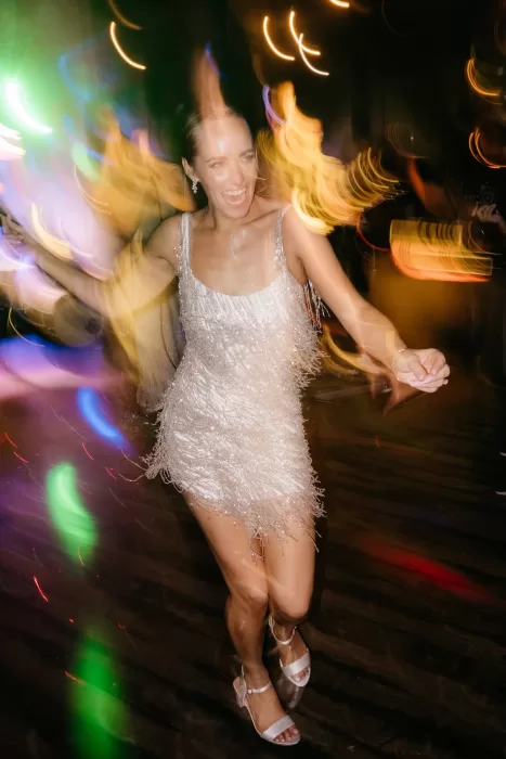 Bride dancing freely on the dance floor at Areias do Seixo, surrounded by colourful lights and movement.