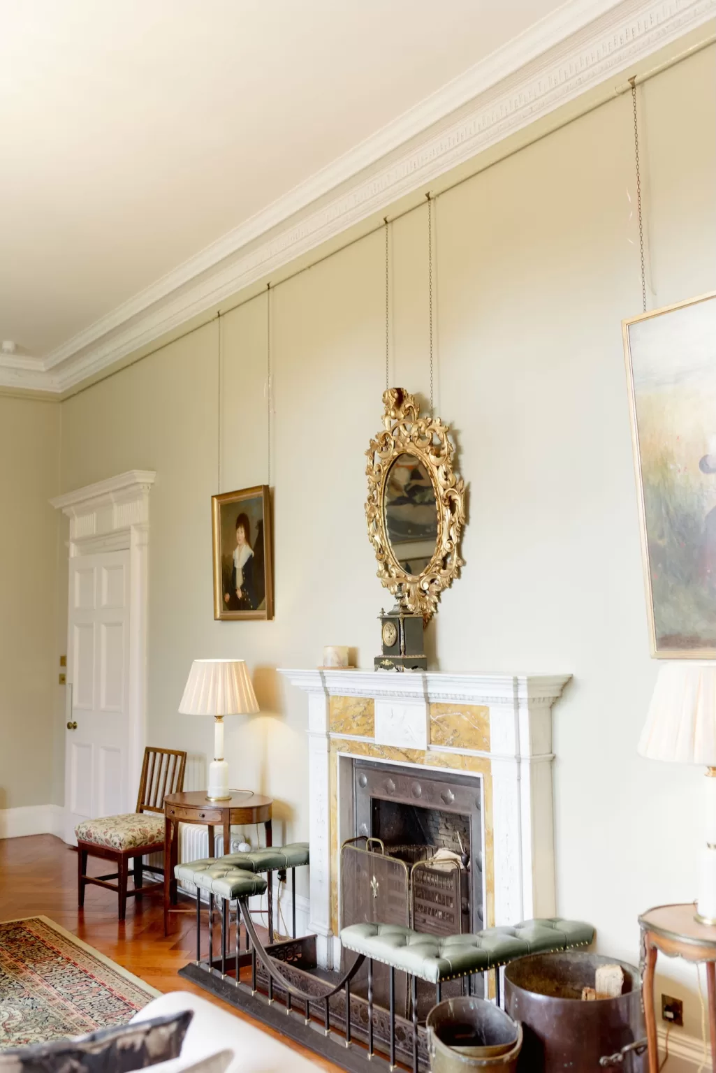 Classic lounge at Boturich Castle featuring an ornate fireplace, antique mirrors and soft lighting for an elegant, historic atmosphere.