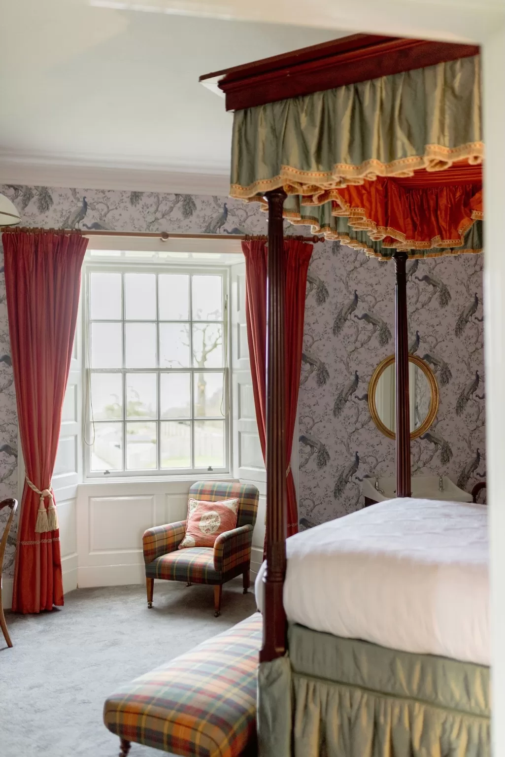 Four-poster bedroom at Boturich Castle with patterned wallpaper, rich fabrics and traditional furnishings creating a warm, romantic retreat.