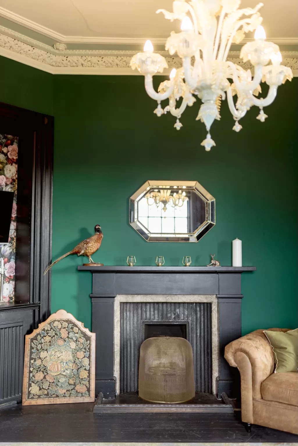 Rich green lounge at Boturich Castle with ornate chandelier, fireplace and antique décor creating a dramatic, intimate atmosphere.
