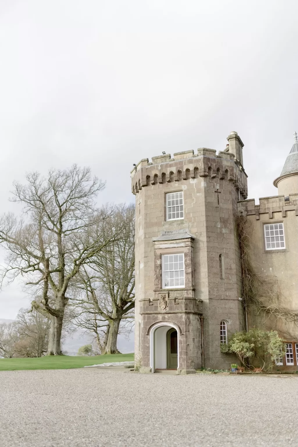 Stone tower entrance at Boturich Castle framed by mature trees and gravel driveway, highlighting the venue’s stately character.
