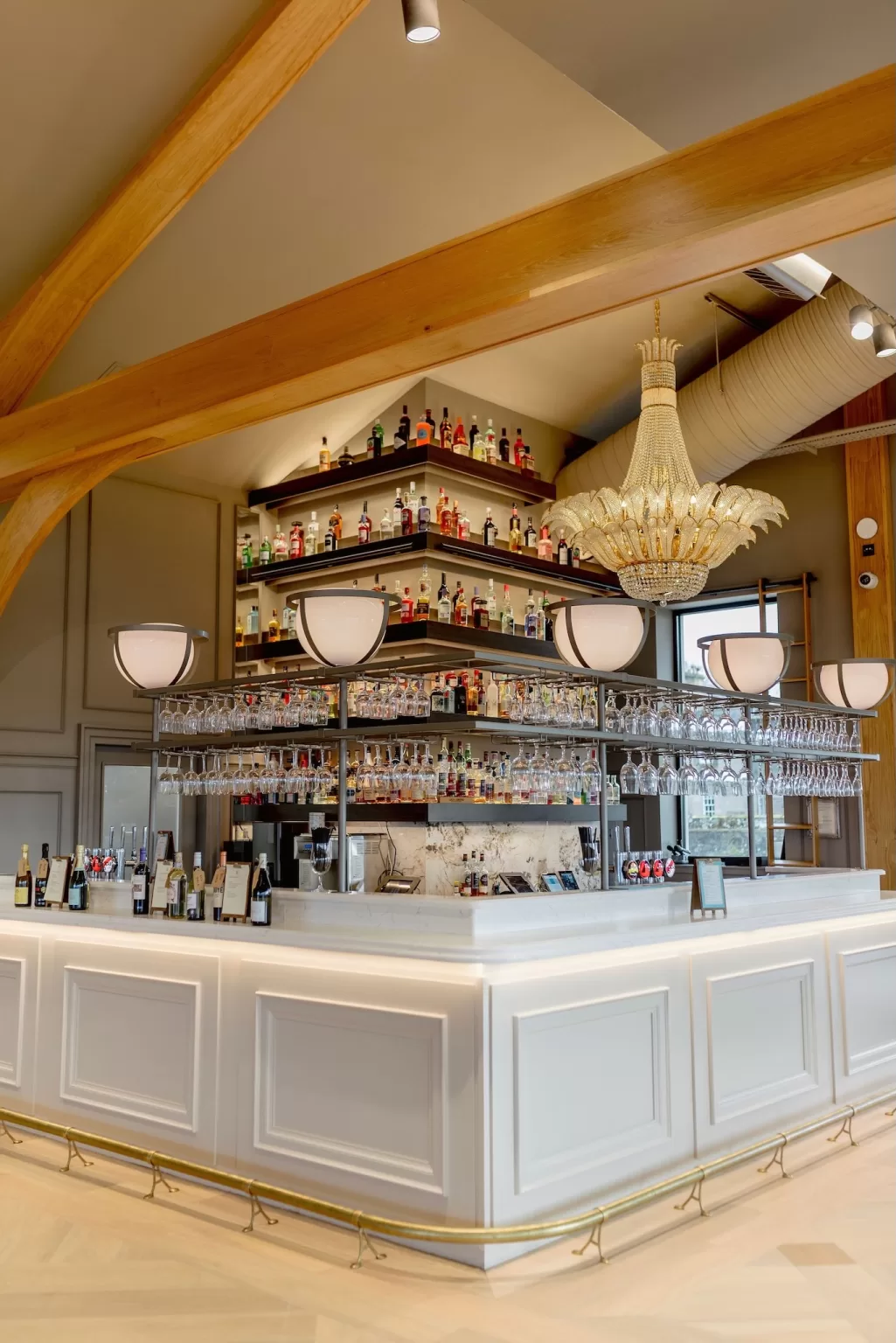 Stylish bar inside the Boturich Pavilion with chandeliers, exposed timber beams and curated bottle displays.