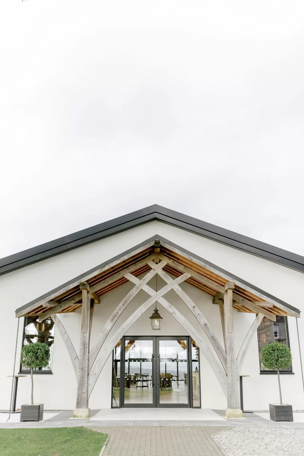 Pavilion entrance at Boturich with timber arches, glass doors and symmetrical landscaping welcoming guests inside.
