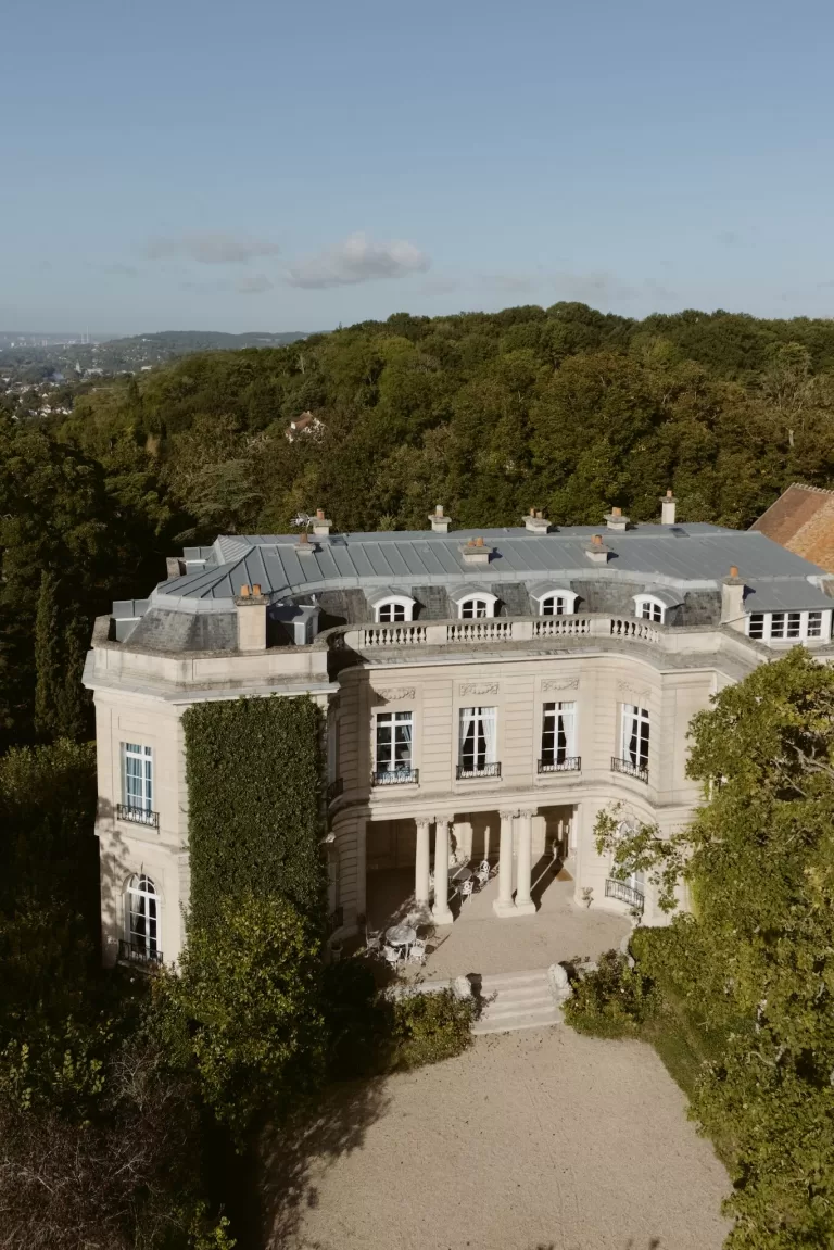 Aerial view of Château du Prieuré d’Evecquemont surrounded by woodland and rolling landscape.