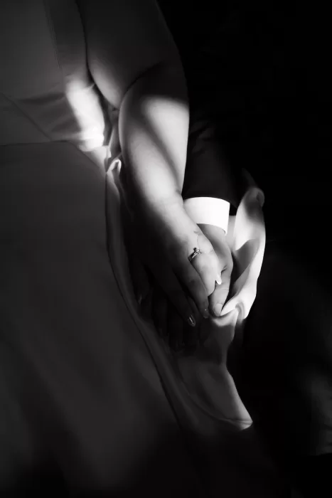 Intimate black and white close-up of the couple holding hands, highlighting the wedding ring and soft fabric textures at Chateau Lill.