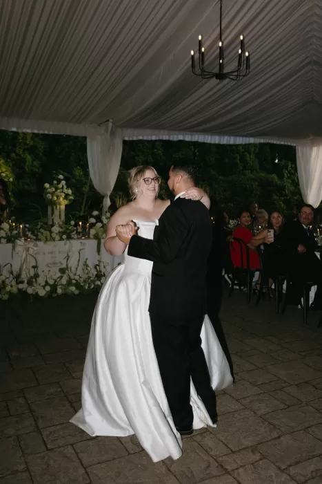 Bride and groom share their first dance beneath a draped marquee at Chateau Lill as guests watch by candlelight.