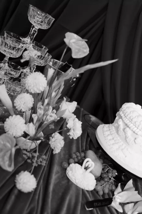 Elegant wedding cake and champagne tower styled with white florals on velvet linens at Chateau Lill, capturing a refined evening reception mood.