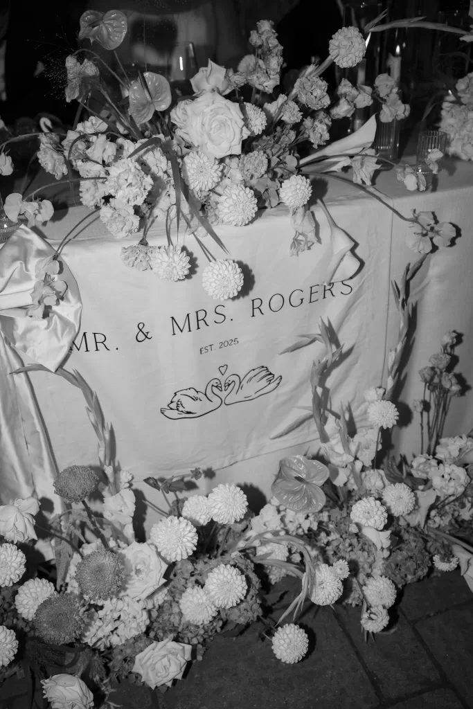 Floral-adorned wedding signage reading “Mr & Mrs Rogers” displayed at Chateau Lill, styled with abundant white blooms.