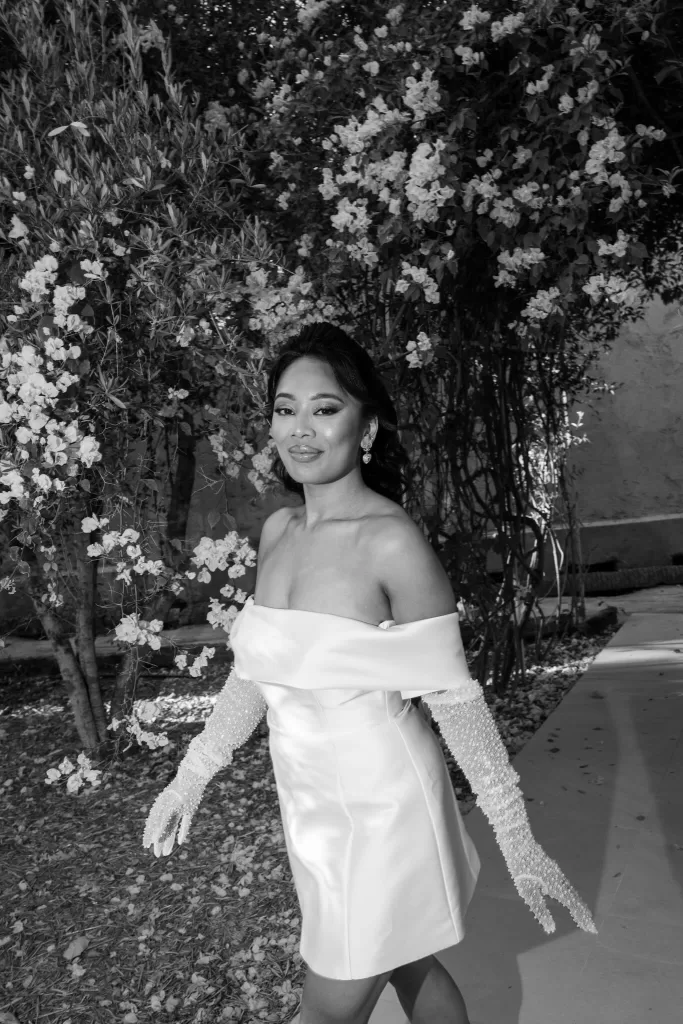 Elegant black-and-white portrait of the bride walking through flowering gardens at Jnane Tamsna.