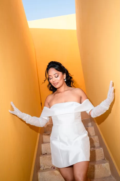 Bride in a chic white mini dress descending a golden-toned stairway at Jnane Tamsna.