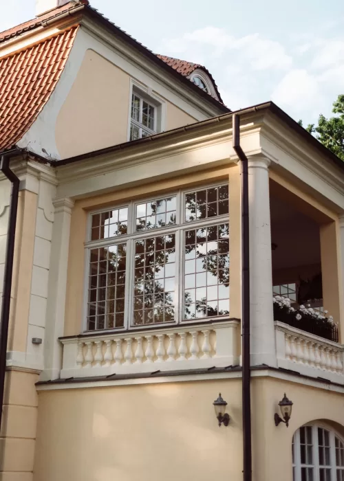 Architectural detail of Malpils Manor showing classic columns, tall windows and traditional rooflines in soft daylight.