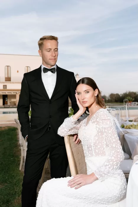 The bride seated beside the groom at a Masseria reception table, her hand resting elegantly on her cheek.
