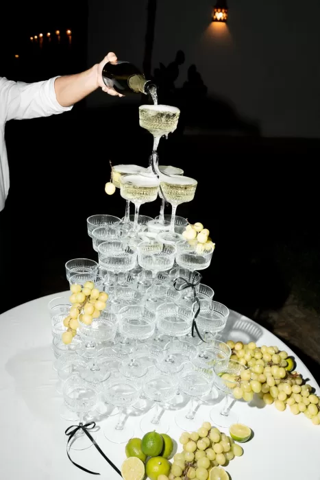 Champagne tower overflowing under night lighting at a Masseria wedding celebration.