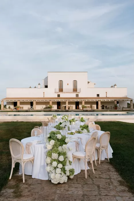 Long outdoor wedding table at Masseria dressed with white linens, green hydrangeas, and candlelight.