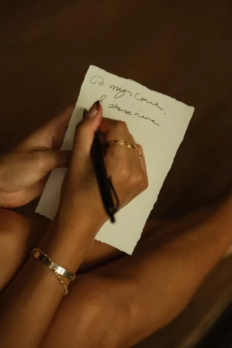 Close-up of handwritten wedding vows held in the bride’s hands, capturing an intimate moment at Ossipoff’s Cabin.