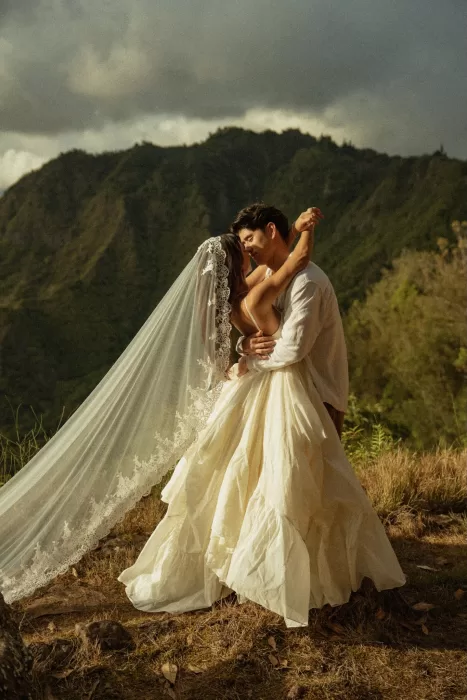 Couple embracing in golden light as the bride’s long veil flows across the mountains near Ossipoff’s Cabin.