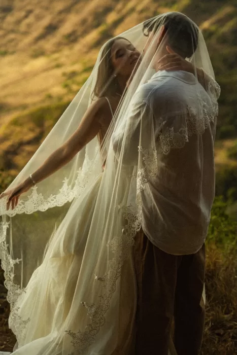Romantic veiled kiss between bride and groom overlooking the landscape at Ossipoff’s Cabin, captured in gentle natural light.