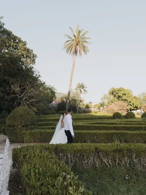 Newlyweds walking together through the formal gardens at Vandelli Botanical Garden in black and white.