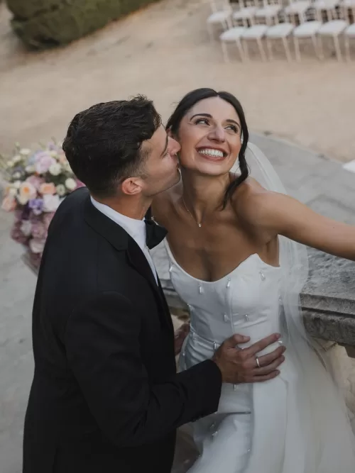Close-up of the groom kissing the bride’s cheek as she smiles during their wedding at Vandelli Botanical Garden.