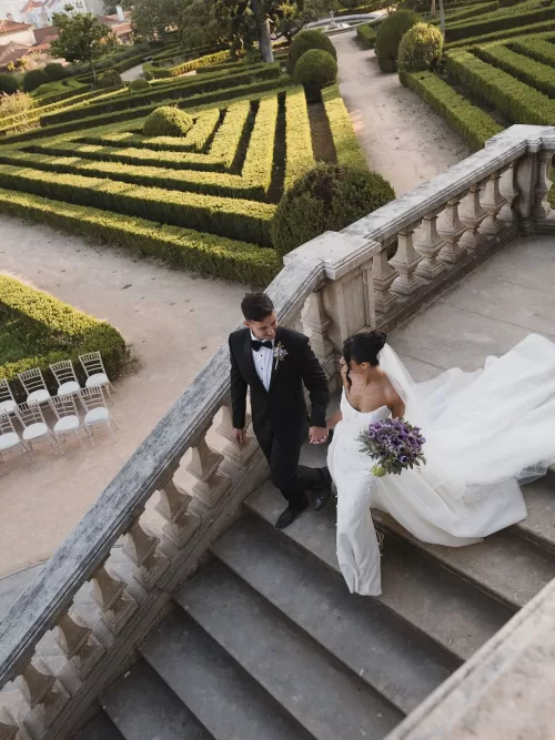 Bride and groom walking down the staircase with sweeping views over the formal gardens at Vandelli Botanical Garden.
