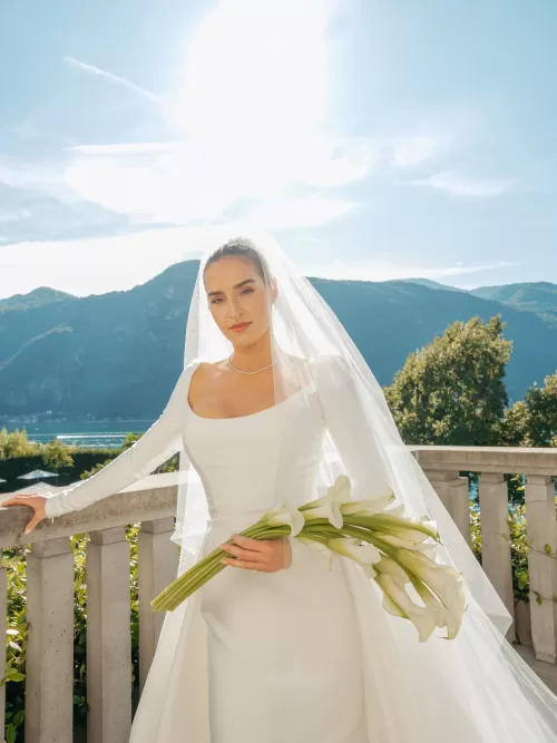 Bride in modern wedding dress holding calla lilies on the terrace at Villa Lario Resort