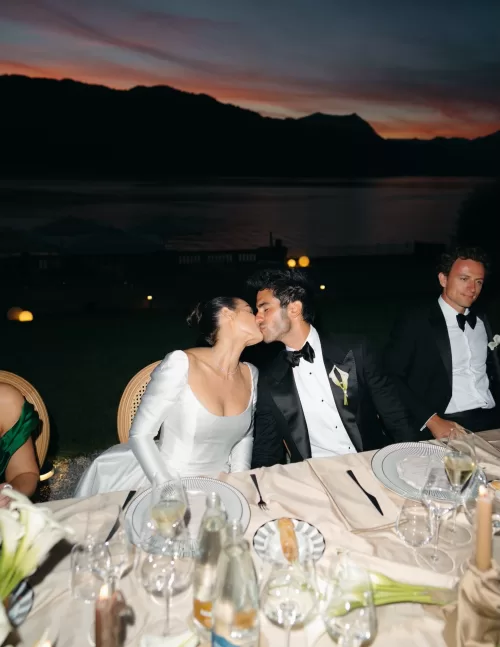 Bride and groom sharing a kiss at the dinner table as the sun sets over Lake Como at Villa Lario Resort