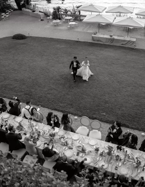 Bride and groom walking away from the reception lawn as guests applaud at Villa Lario Resort