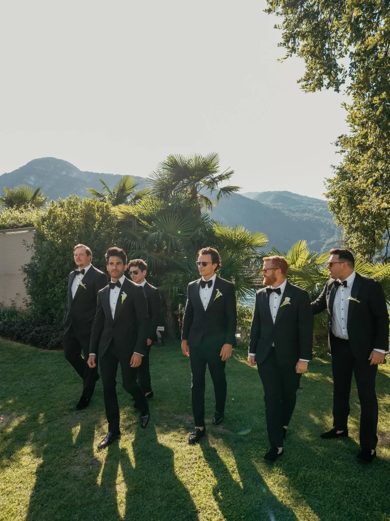 Groom and groomsmen in black tie walking through the garden with lake views at Villa Lario Resort