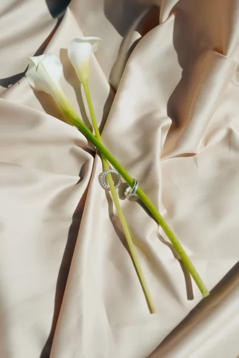 Wedding rings styled with calla lilies on soft silk fabric at Villa Lario Resort